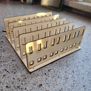 May include: A wooden organizer with multiple compartments, perfect for storing small items like craft supplies or jewelry. The organizer is made of light brown wood and has a simple, modern design.