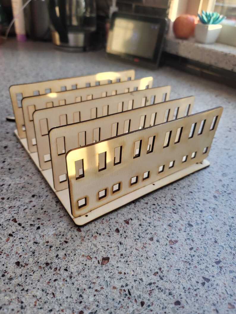 May include: A wooden organizer with multiple compartments, perfect for storing small items like craft supplies or jewelry. The organizer is made of light brown wood and has a simple, modern design.