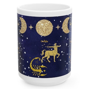 May include: White ceramic mug with a dark blue background featuring gold glitter accents of the moon phases, stars, and zodiac symbols. The mug has a Sagittarius and Scorpio design with the name "Goldie" in gold lettering.