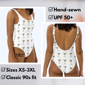 May include: White one-piece swimsuit with a pattern of martini glasses. The swimsuit has a scoop neck and a classic 90s fit. The text "Hand-sewn" and "UPF 50+" is visible on the image. The text "Sizes XS-3XL" and "Classic 90s fit" is also visible on the image.