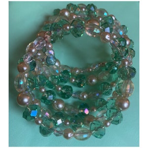 May include: A multi-strand bracelet made of green and iridescent glass beads and cream-colored pearls.