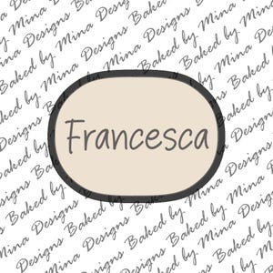 May include: A beige oval with a black outline and the name "Francesca" written in black inside. The oval is on a white background with the text "Baked by Mina Designs" repeated in a pattern.