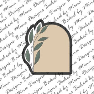 May include: A beige arch-shaped cookie cutter with a leafy design on the left side. The cutter is outlined in black.
