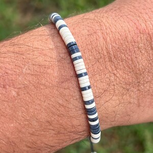 Puede incluir: Un brazalete de rayas blancas y negras con cierre de cordón.