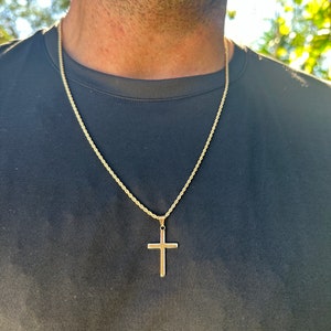 May include: A gold chain necklace with a simple gold cross pendant.
