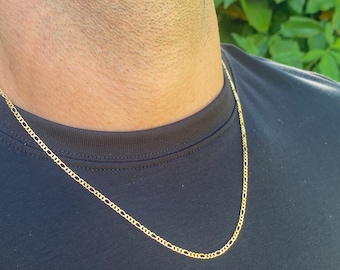Könnte beinhalten: Eine goldene Kettenkette, die von einer Person mit einem schwarzen Shirt getragen wird.