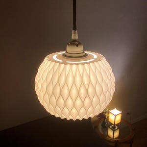 May include: A white, textured, round pendant light fixture with a white cord and a white ceiling mount.