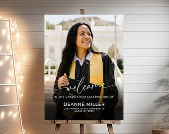 May include: A black and white welcome sign with a photo of a graduate wearing a yellow and black graduation gown. The sign reads "Welcome to the graduation celebration of Deanne Miller, California State University, Class of 2029."