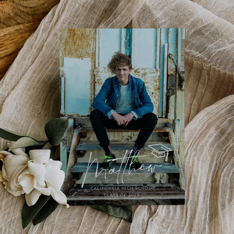 May include: A graduation announcement with a photo of a young man sitting on a set of stairs. The announcement has a white background with the text "Matthew" in a handwritten font, "California High School", and "Class of 2029".
