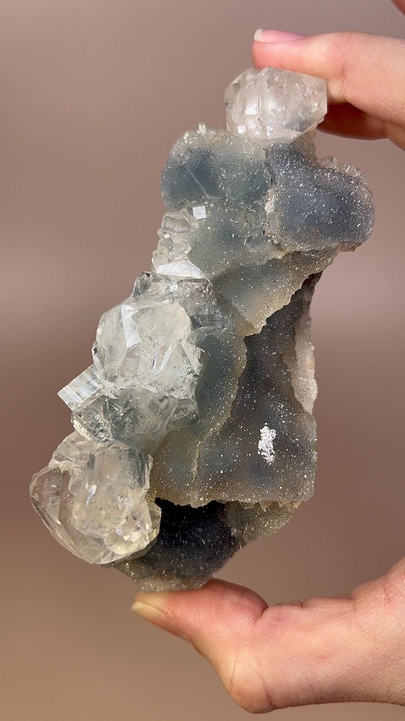 May include: A cluster of translucent, light blue and clear quartz crystals. The crystals have a rough, textured appearance and are arranged in a layered formation. The overall shape is irregular, with sharp edges and points.