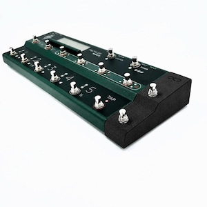 May include: A dark green guitar effects pedal with multiple silver foot switches and a small digital display. The pedal has the text "Profiler Remote" and numbers 1 through 5. The pedal is on a white background.