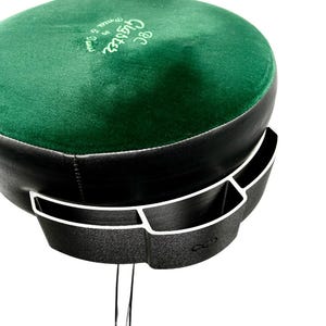 May include: A green velvet-covered stool with a black base and a black plastic holder with three compartments. The stool has a silver metal leg and the text "OG  Glasses  from the  ground up" is embroidered on the top.