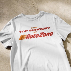 Puede incluir: Camiseta blanca con el texto "I got top surgery at AutoZone" en rojo y naranja.