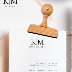 May include: A black Trodat self-inking stamp and a wooden handle rubber stamp featuring the monogram KM. The stationery set includes a pale pink envelope with a wax seal, a white card with deckled edges, and an envelope printed with The Future Mr. and Mrs. Robinson, 345 Coral Cove #201, Dana Point, CA 92624.
