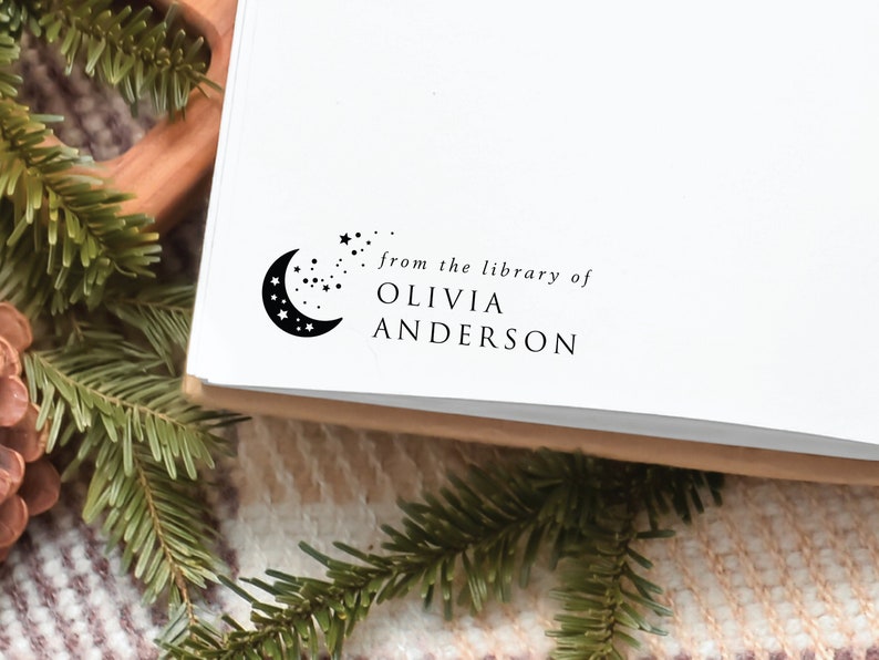 May include: A black and white stamp with a crescent moon and stars. The text "from the library of OLIVIA ANDERSON" is below the image.
