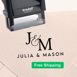 May include: A black Trodat Printy 4914 self-inking stamp positioned above a stamped impression on textured paper. The impression features the black text J&M in a serif font, followed by the text JULIA & MASON in a clean, sans-serif typeface.