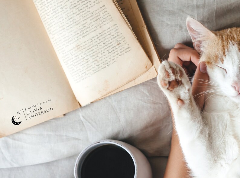 May include: A close-up of a book with a stamp that reads "from the library of OLIVIA ANDERSON". A cat is being petted by a hand, and a cup of coffee is in the background.
