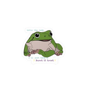 Può includere: Un adesivo con un ranocchio dei cartoni animati verde e marrone. Il ranocchio ha grandi occhi neri e sorride. Il testo sull'adesivo dice "&&for the lady" e "I'll just have a... Sweet lil treat."