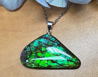 May include: A triangular pendant necklace with a vibrant, iridescent gemstone. The stone displays a mosaic of green, blue, and purple hues, set in a silver-toned metal. The chain is delicate and silver, creating an elegant accessory.