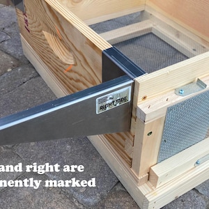 Op de afbeelding: Een houten bijenkorf met een metalen frame en een gaas. Het frame is gemarkeerd met "Right Side".