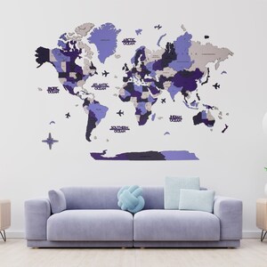 May include: A purple and blue world map made of wood with the names of the oceans printed on it. The map is mounted on a white wall above a light purple sofa with a blue throw pillow.