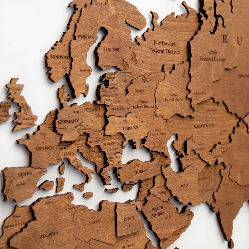 May include: A wooden world map puzzle with the continents of Europe, Asia, and Africa. The map is made of individual pieces that fit together to form a complete map. The map is brown in color and has a natural wood finish.