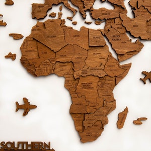 May include: A wooden world map puzzle with the continent of Africa assembled. The puzzle pieces are labeled with the names of countries in Africa. The puzzle is on a white background.