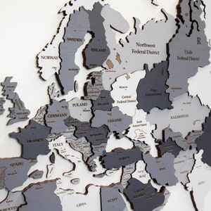 May include: A detailed wooden map of Europe with each country outlined in grey and labelled with its name. The map is divided into federal districts of Russia, with each district labelled in black text.