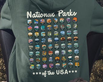 May include: A dark green hooded sweatshirt featuring a graphic on the back with the text "National Parks of the USA" and a grid of small, colorful illustrations depicting various landscapes and natural landmarks across the country.