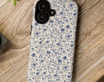 May include: A white phone case with a blue floral pattern. The case has a black camera lens cutout.