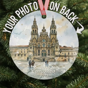 May include: Round Christmas ornament featuring a watercolor painting of the Santiago de Compostela cathedral. The ornament has a red ribbon for hanging and the text "YOUR PHOTO ON BACK". The bottom of the ornament reads "Santiago de Compostela 2025".