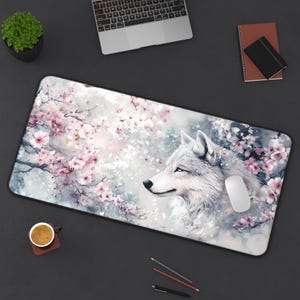 May include: A white wolf with blue eyes is depicted in a watercolor style against a background of pink and white cherry blossoms. The wolf is looking to the right of the image. The background is a soft blue and gray.