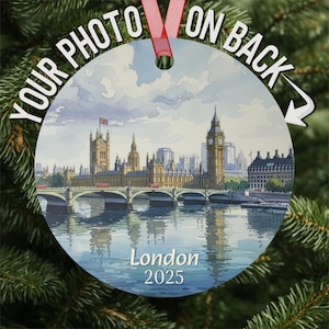 May include: Round Christmas ornament featuring a watercolor painting of London's skyline, including Big Ben and the Houses of Parliament. The ornament has the text "Your Photo On Back" and "London 2025". It is hanging from a red ribbon.