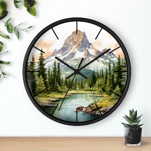 May include: Black clock with a watercolor image of a mountain range, a lake, and trees. The clock face has black hands and black Roman numeral markings.