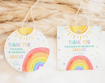 May include: Two round and square thank you tags with a rainbow and sun design. The text on the tags reads "Thank you for making my birthday 80 bright, love Mathew".