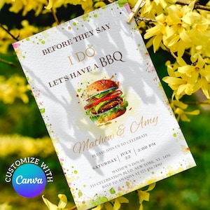 May include: A white invitation with watercolor splatters in shades of pink, green, and blue. The invitation features a cartoon burger with a gold ring on top and the text "Before they say I do, let's have a BBQ". The invitation is for Mathew and Amy's wedding celebration on Saturday, July 22nd at 2:00 PM. The address is 333 Celebration Blvd, New York, NY, 3456. RSVP to Amanda at 123.456.7890.