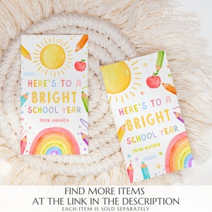 May include: Two printable cards with a watercolor illustration of a sun, rainbow, pencils, and an apple. The text on the cards reads "Here's to a bright school year" with a space for a name.