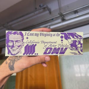 May include: A rectangular bumper sticker with a light yellow background and purple graphics. The sticker features a portrait of a smiling man, text that reads "I Lost my Virginity at the California Department of Motor Vehicles DMV", and a vintage car illustration.