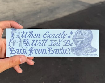 Peut inclure: Un autocollant rectangulaire bleu clair avec une illustration bleu foncé d'une personne aux longs cheveux à gauche et d'un casque de chevalier à droite. Le texte indique : When Exactly Will You Be Back From Battle? et FREDDY TYLER PAUL.