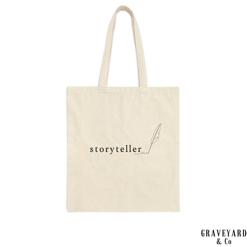 May include: A white canvas tote bag with black text that reads "storyteller" and a simple line drawing of a feather.