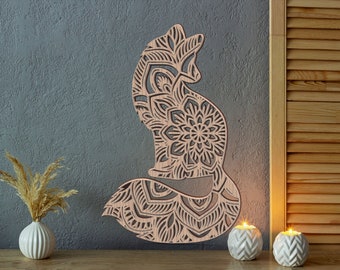 May include: A wooden fox wall art piece with intricate mandala-style patterns. The fox is in a seated position, with a detailed design throughout its body. The art is displayed against a gray wall, with decorative candles and a vase with dried plants.
