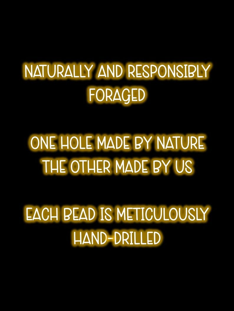 May include: A black graphic with gold-colored text that reads: NATURALLY AND RESPONSIBLY FORAGED, ONE HOLE MADE BY NATURE THE OTHER MADE BY US, EACH BEAD IS METICULOUSLY HAND-DRILLED. The text is presented in a clean, sans-serif font style.