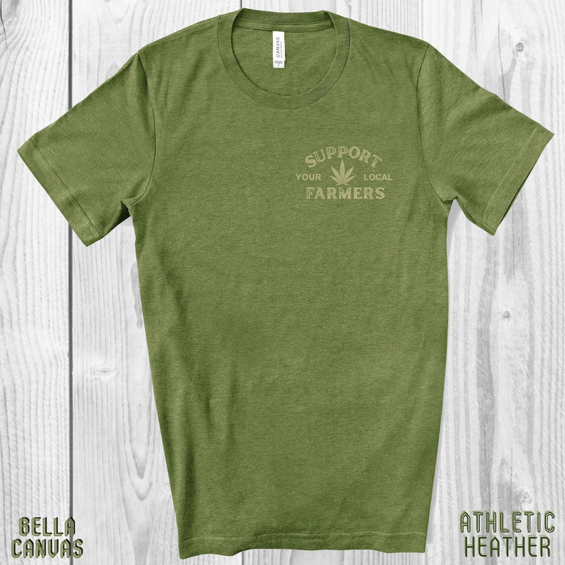 K&ouml;nnte beinhalten: Gr&uuml;nes T-Shirt mit einer Grafik eines Marihuana-Blattes und dem Text "Unterst&uuml;tze deine lokalen Bauern".