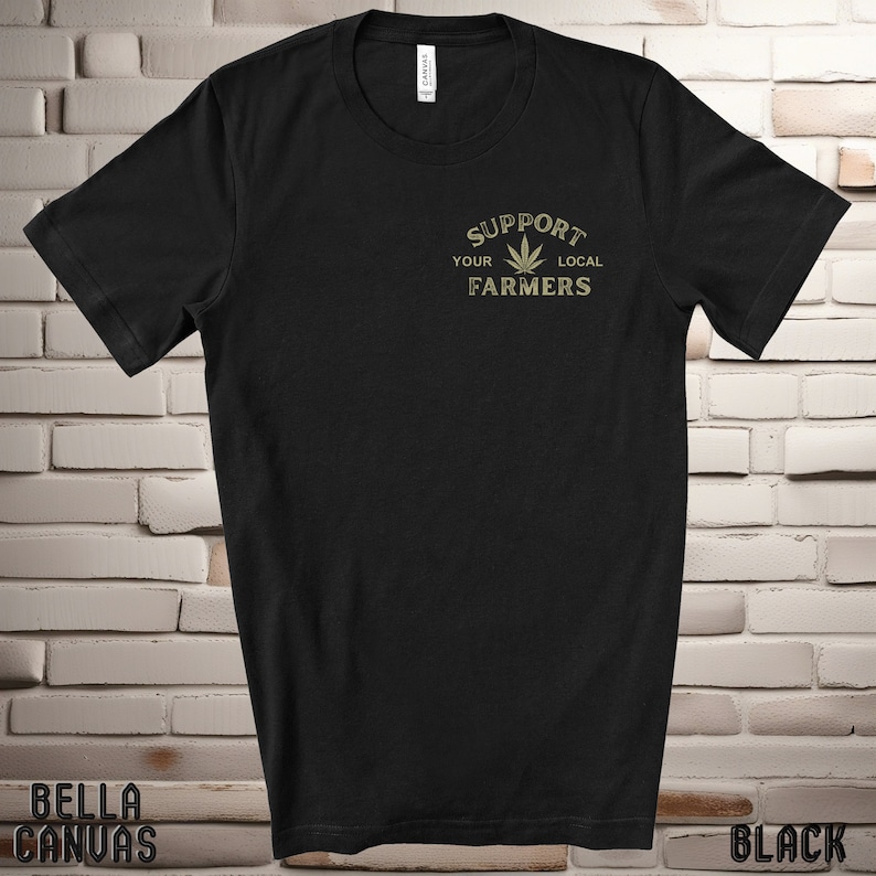 K&ouml;nnte beinhalten: Schwarzes T-Shirt mit einer goldenen Grafik, auf der "Unterst&uuml;tze deine lokalen Bauern" mit einem Marihuana-Blatt-Design steht.