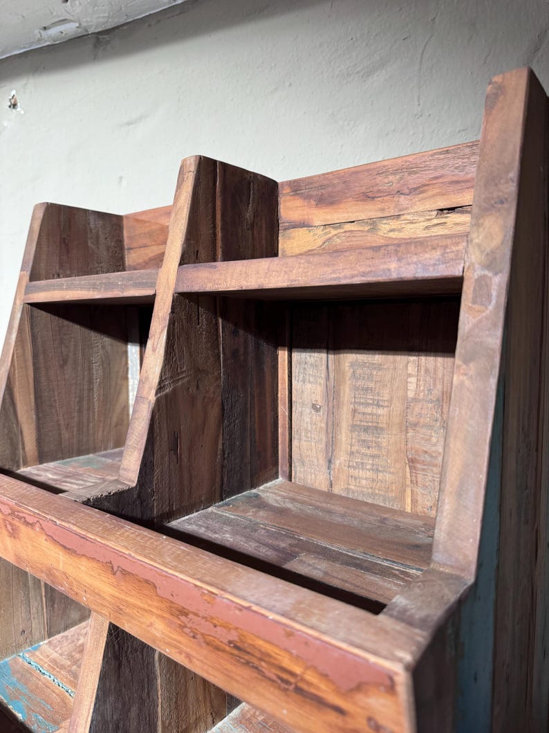 May include: A brown wooden storage unit featuring two open compartments on the top tier, constructed from reclaimed wood with visible grain patterns, rough textures, and a sturdy frame with angled side panels and a horizontal support beam.