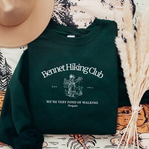 May include: A dark green sweatshirt with a white graphic print that says "Bennet Hiking Club Est. 1813 We're very fond of walking Derbyshire".
