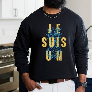 May include: Black sweatshirt with a pineapple graphic and the text "JE SUIS UN" in yellow.