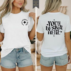 Può includere: Una t-shirt bianca a maniche corte con un piccolo logo circolare nero sul petto sinistro con il testo YOUR DESIGN HERE e una grande grafica nera sul retro con il testo YOUR DESIGN HERE in un carattere ondulato con piccoli cuori.