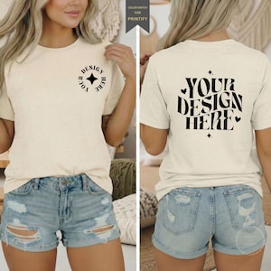 以下が含まれることがあります： クリーム色のTシャツ。背面に黒で「YOUR DESIGN HERE」の文字と前面に小さなデザインが施されています。モデルはライトブルーのデニムショーツを着用しています。このシャツはデザイン配置のモックアップです。