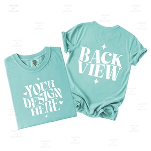 May include: A light teal t-shirt featuring white text that reads YOUR DESIGN HERE with small star and heart accents on the front, and a second t-shirt showing the back with white text that reads BACK VIEW and star accents.